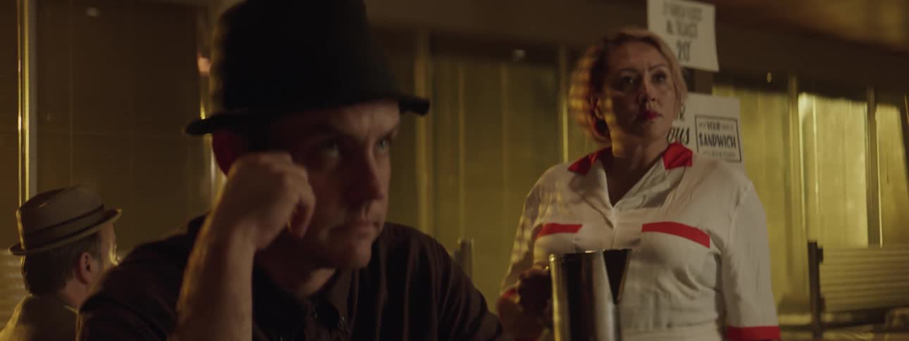 A man and a waitress in a cafe look upset