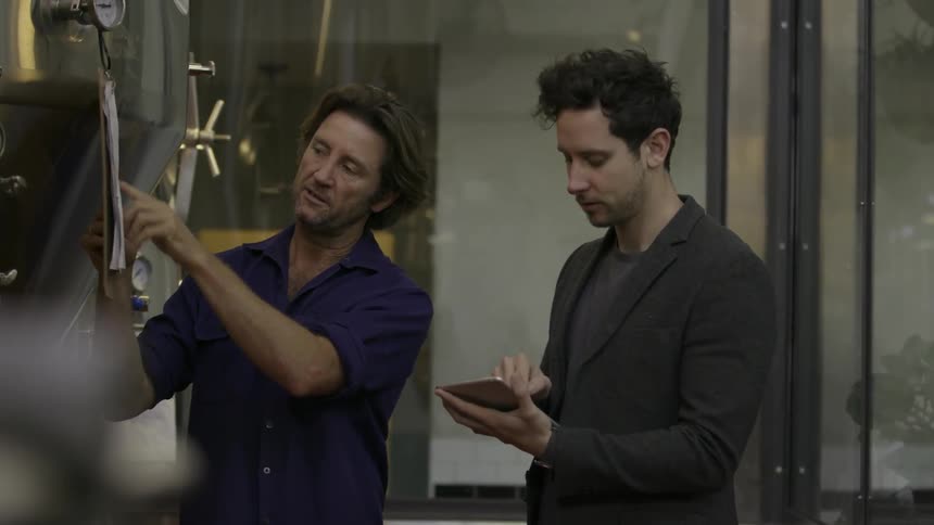 Man enters data into a device while another man points to a clipboard