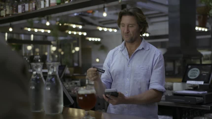 Man working in a business takes a customer's card and runs it through a machine