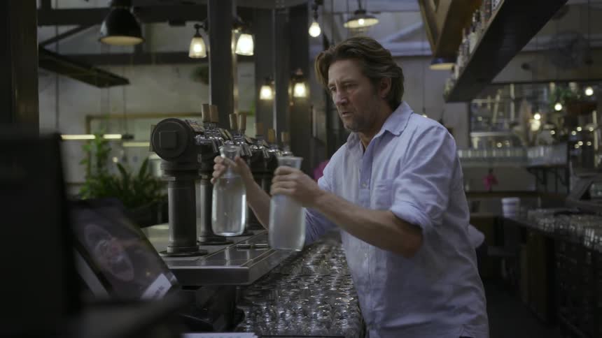 Man puts down a tray of jars and puts water jugs aside