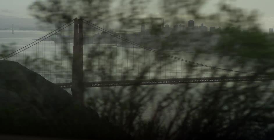 A suspension bridge is being filmed along a roadway