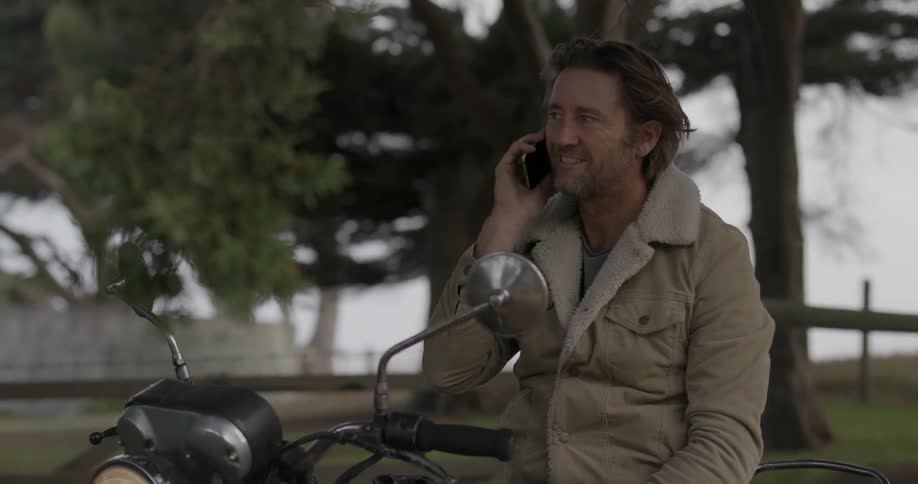 A man on a motorcycle talks on the phone