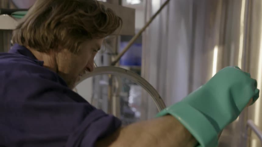A man places a big stirring blade through an opening of a machine