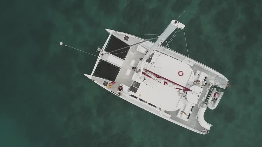 A large boat is white and has it's sails down
