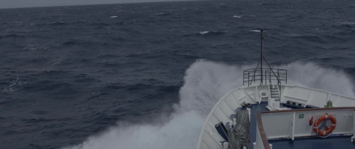A ship smashes through waves on the open ocean in storm