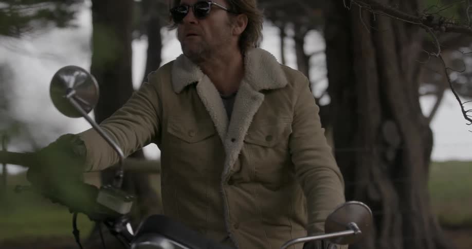 A man puts on his sunglasses and starts his motorcycle