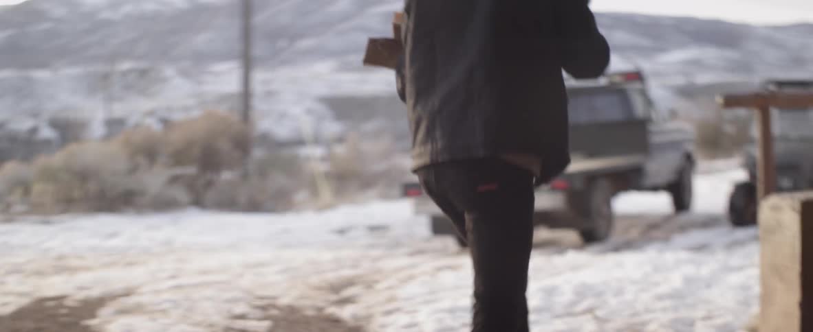 Man gathers up firewood and walks towards a truck