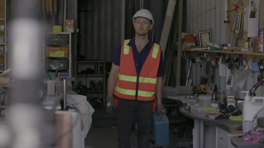 A worker wears an orange vest in a workshop