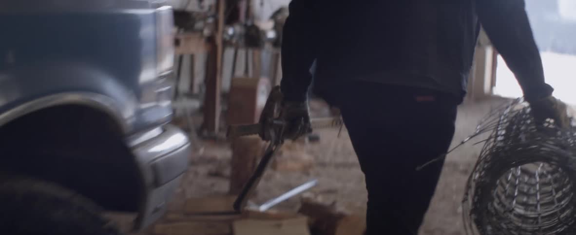 A man unloads tools and a roll of mesh from a truck