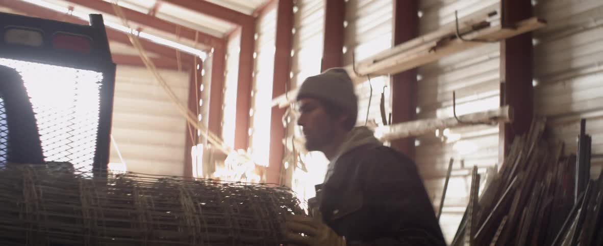 Man picks up a large roll of wire