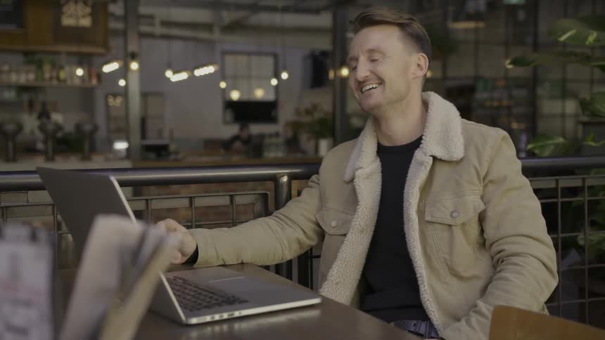 Man smiles and talks looking into a laptop