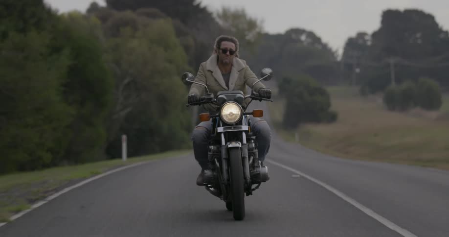 A man is riding his motorcycle along a country road