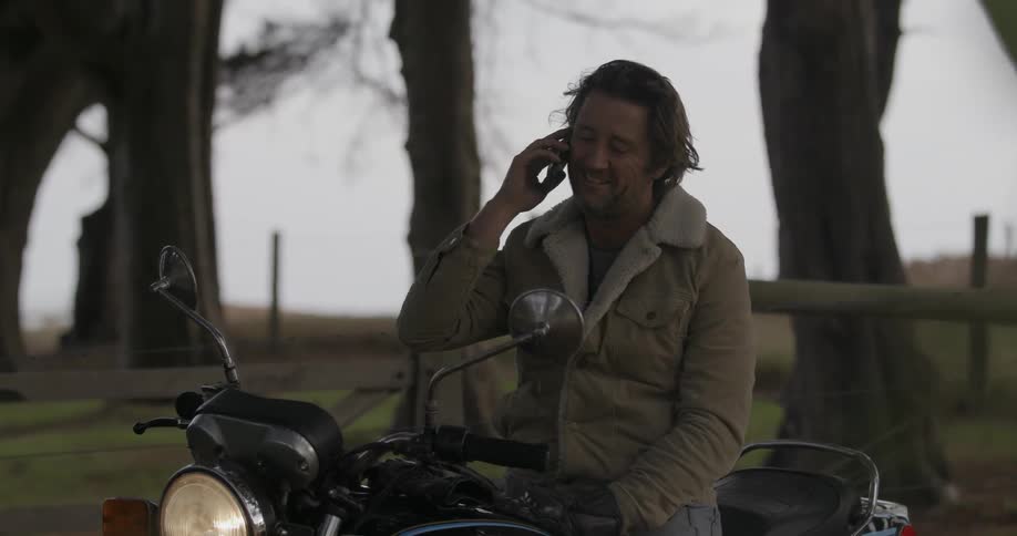 Man sitting on a motorcycle talks on his phone