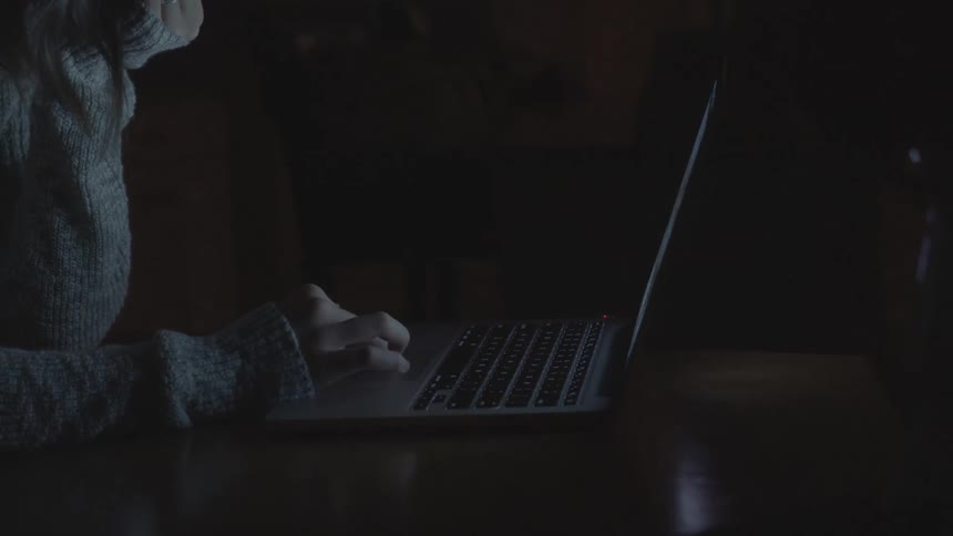A woman sits at a table with a laptop