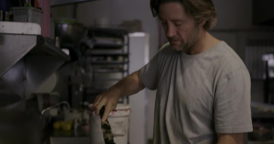 A man is putting frosting on pastries