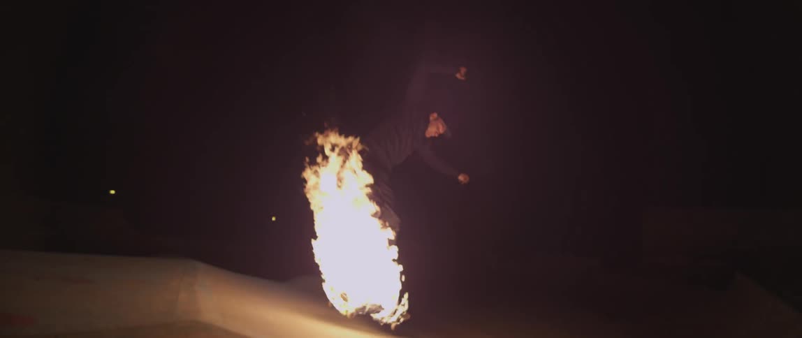 Young man rides on a flaming skateboard and does a jump