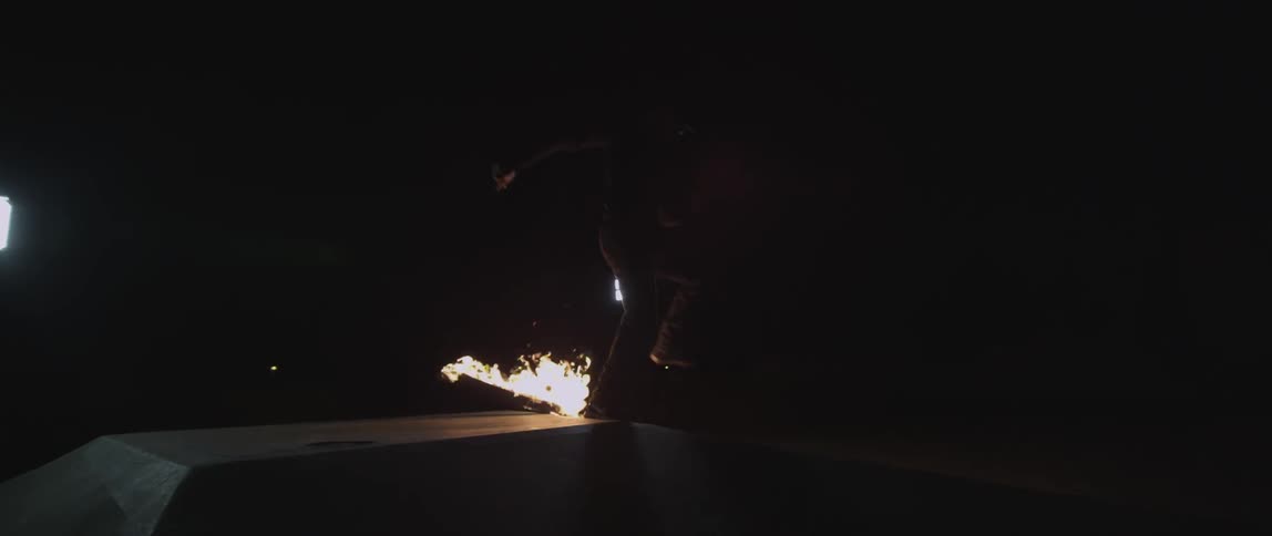 A man jumps a skateboard that is on fire