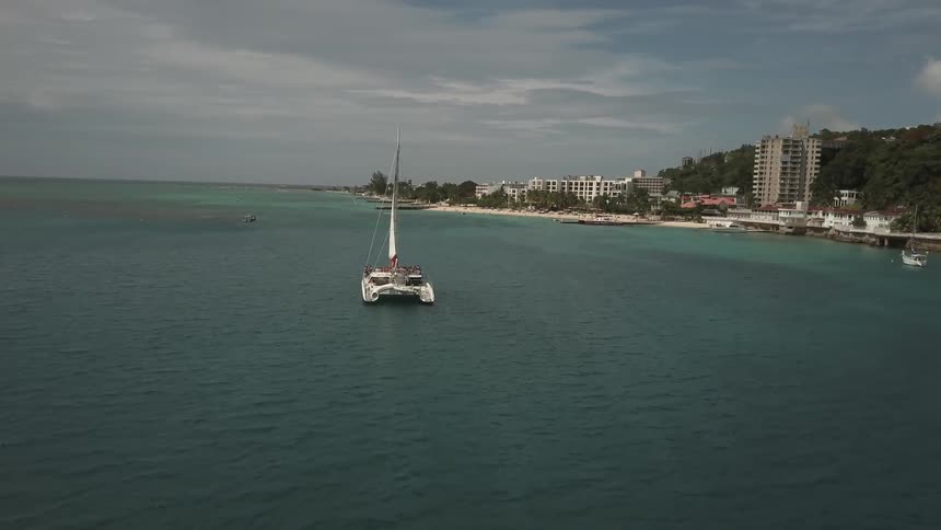 A boat floats just off the ocean coast