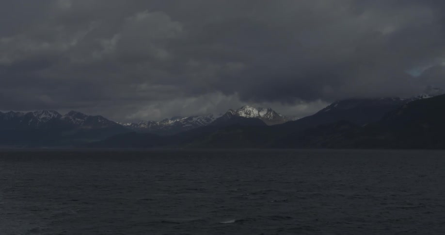 The mountains beyond the water are surrounded by dark clouds