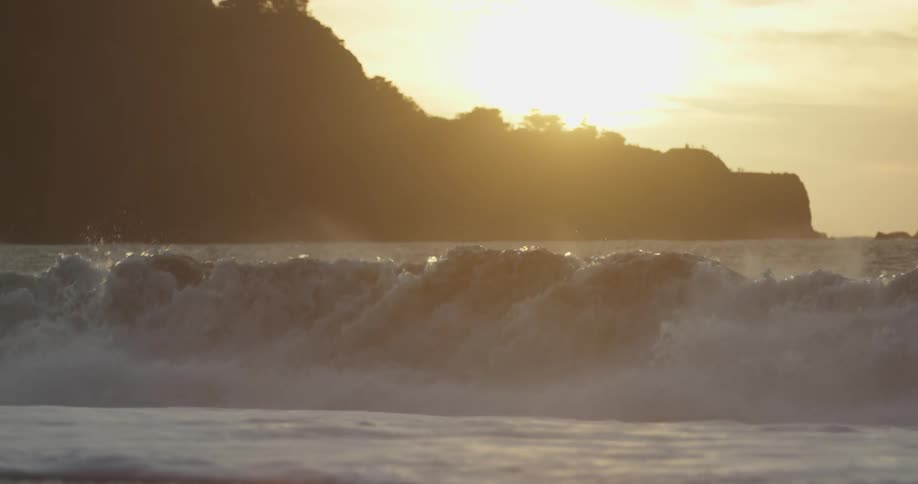 Ocean waves crashing up onto beach as sun sets