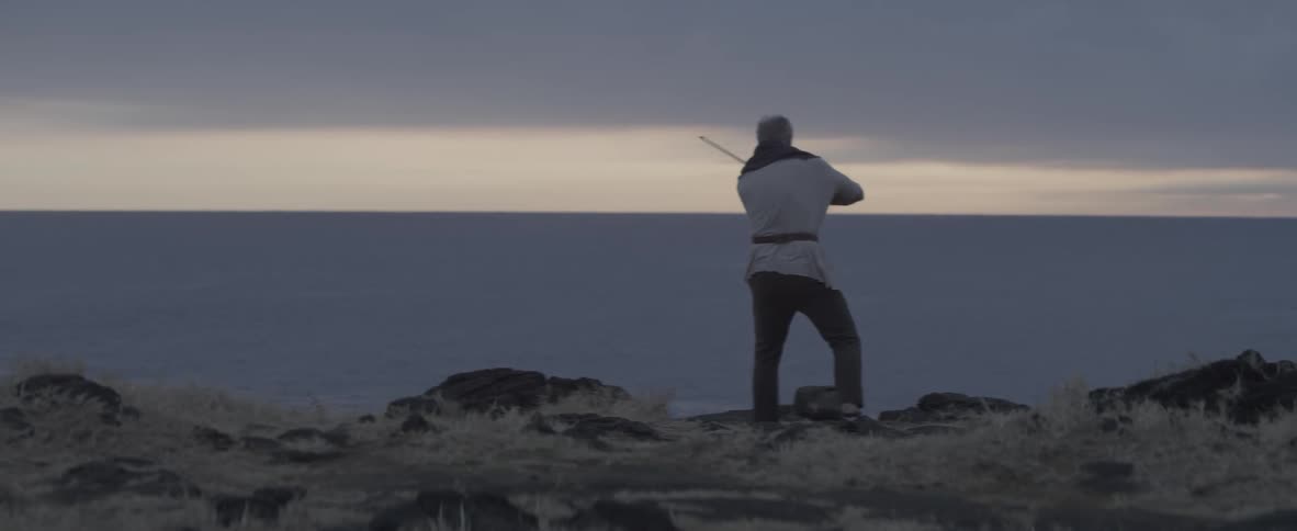 A man with a violin running towards the ocean before starting to play