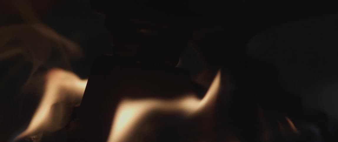 The flames of a fire lap around a dark object