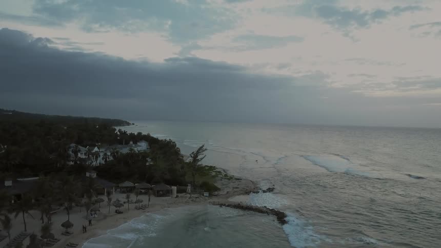 Waves roll in on a beach under a cloudy sky