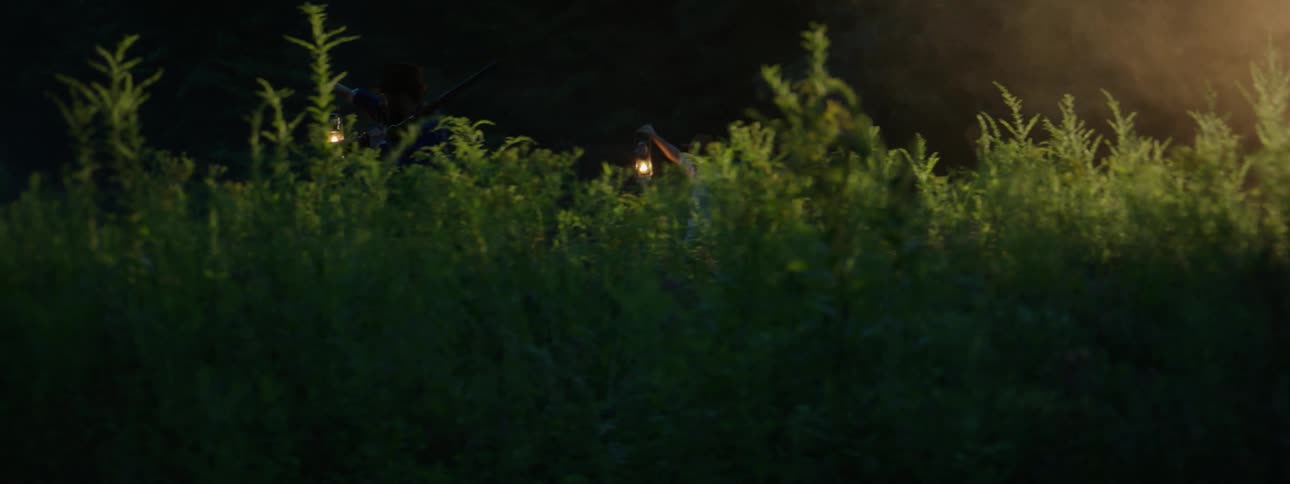 Two men hold lanterns aloft as they search at night