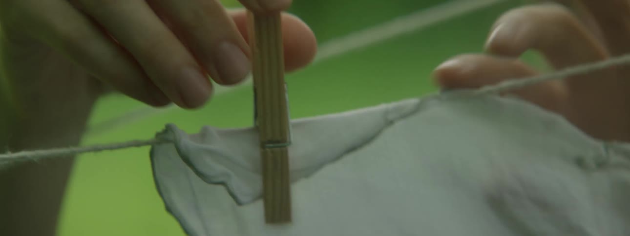 A person pins a white cloth to a clothes line