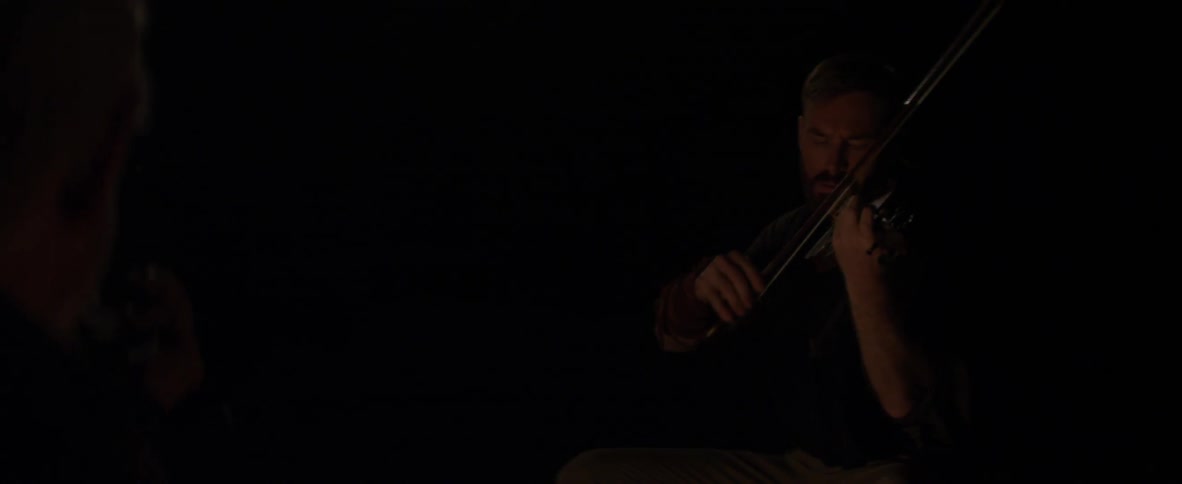 Man plays a violin in dim light