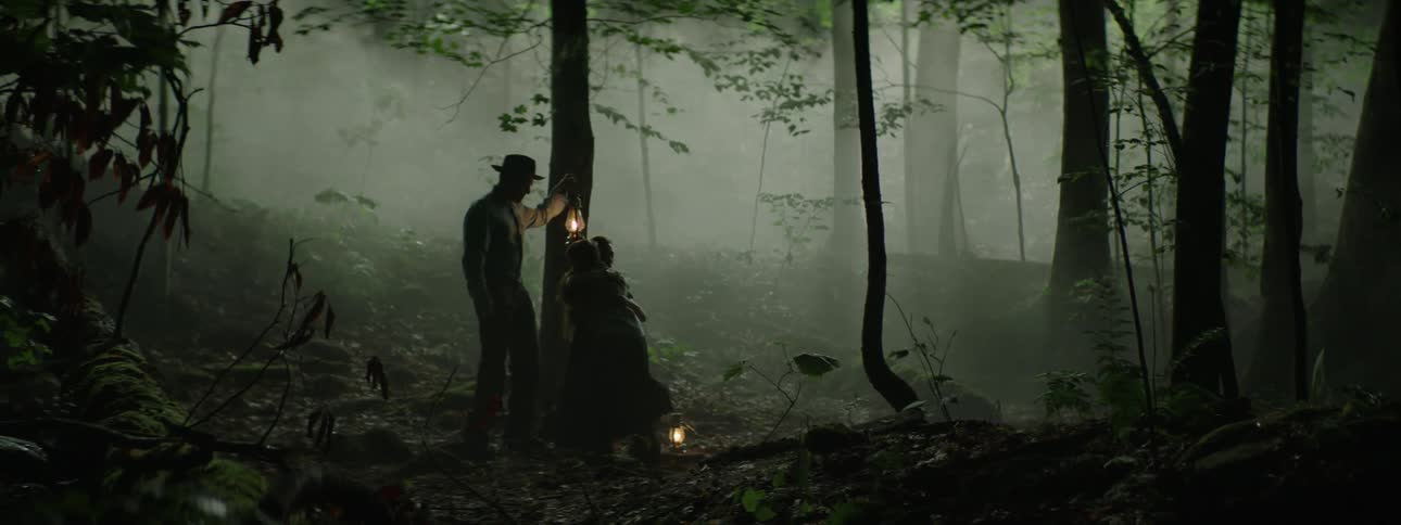 Man and woman carrying lanterns come across a young child in the woods