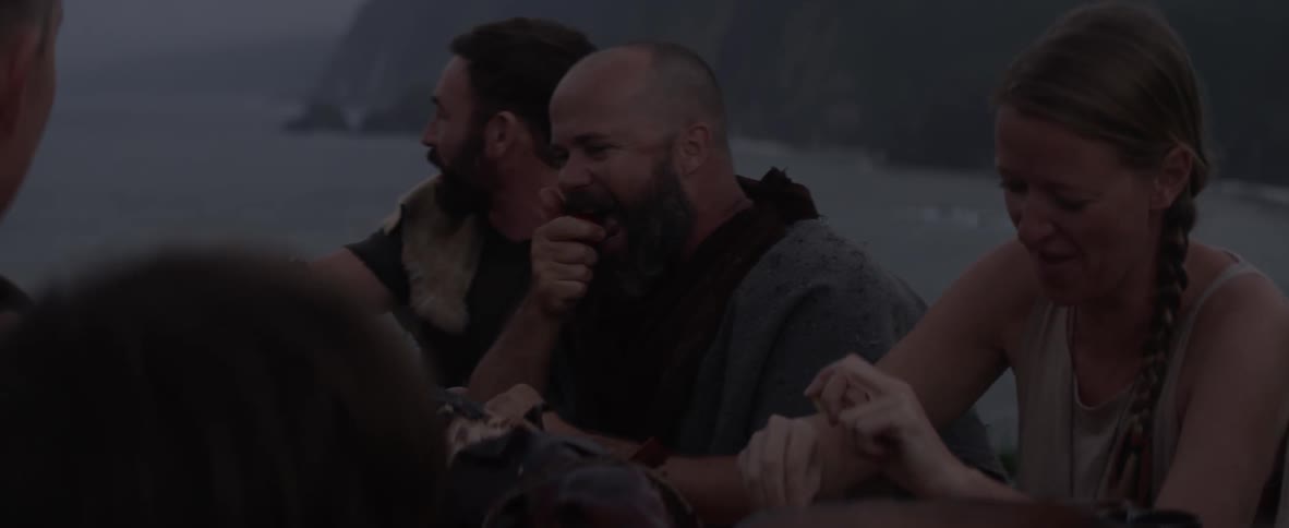 People sit together laughing and eating outdoors