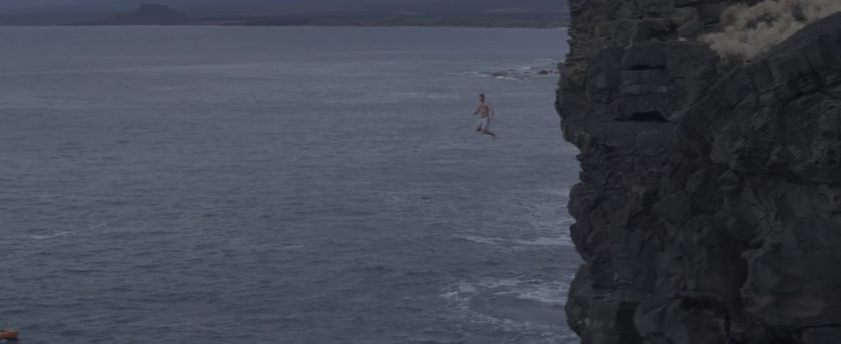 A man jumps into the ocean from a high cliff