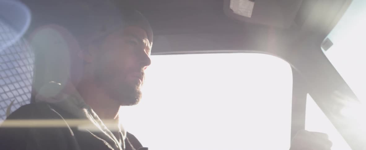 Bearded man wearing a toque drives his vehicle down the road