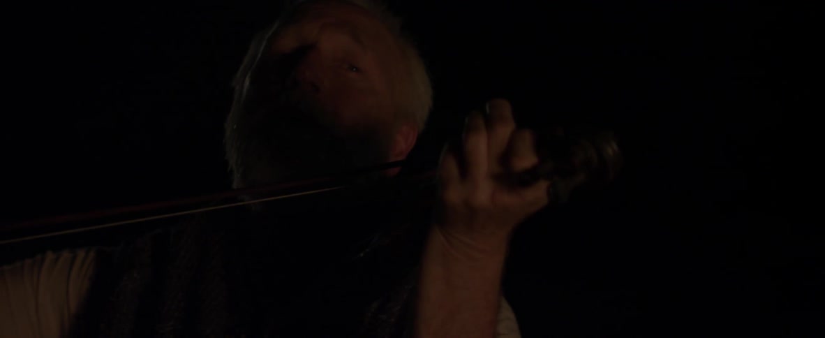 A man is playing the violin at night