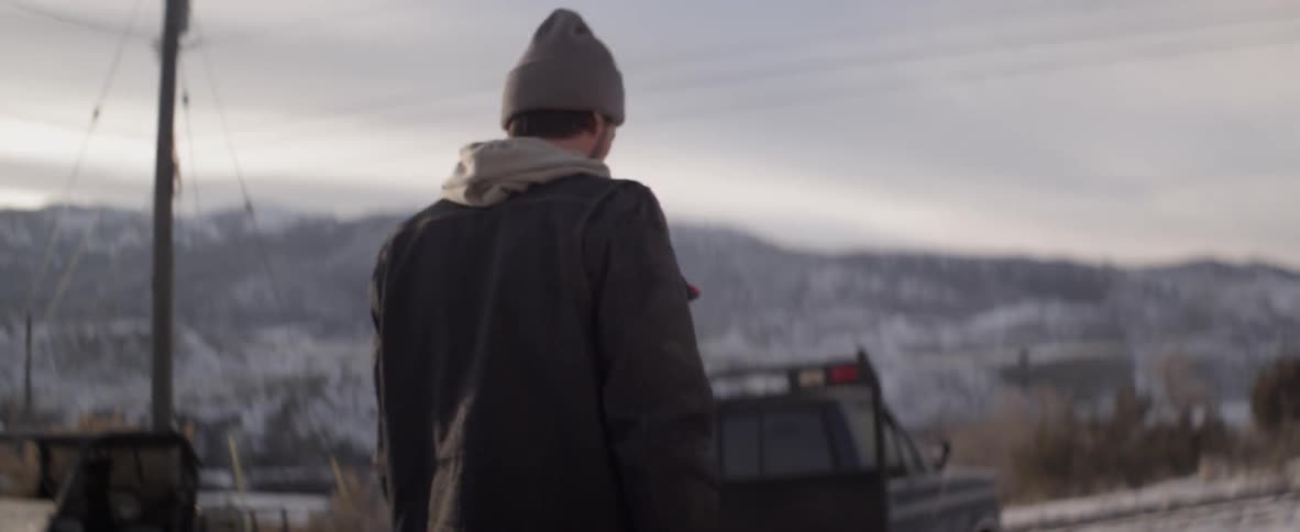 A man hikes in the snow on a cloudy day