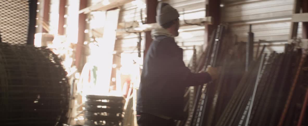 A man lifts metal beams in a warehouse
