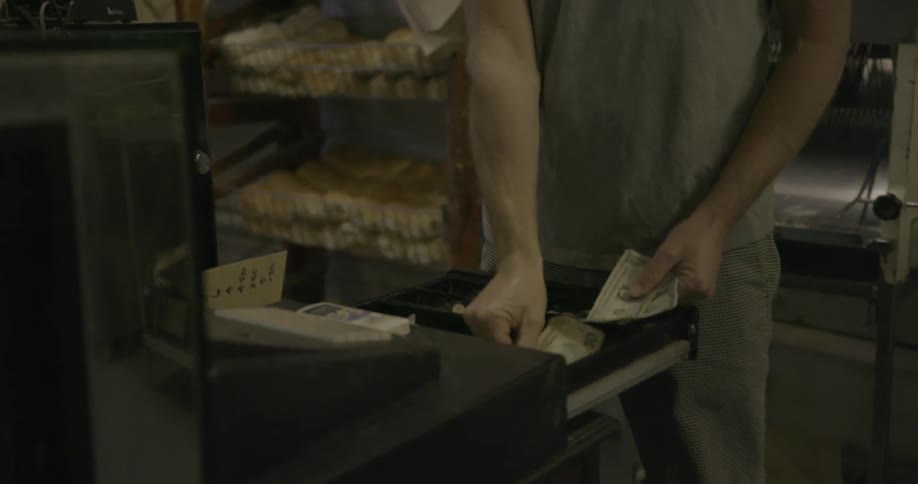 A man walks over and puts money in the register