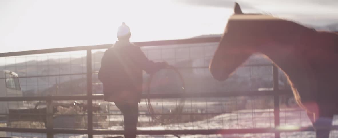 Man carrying wire throws it over a fence