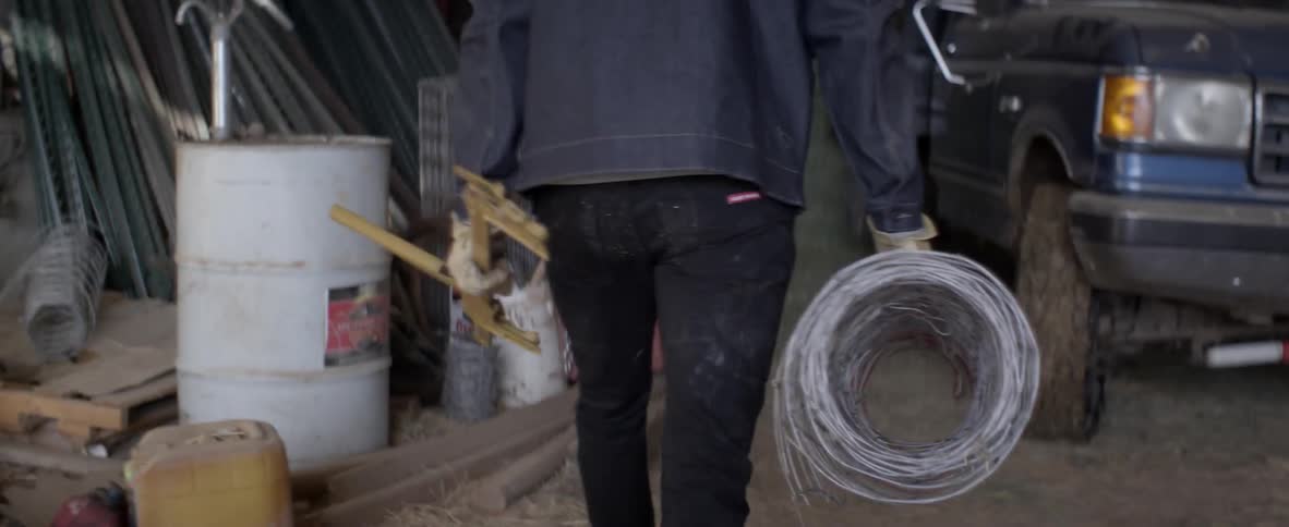 Man carries a roll of barbed wire back to a truck