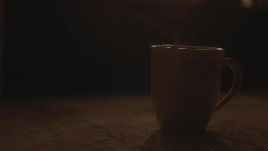 Steaming coffee cup in flickering light