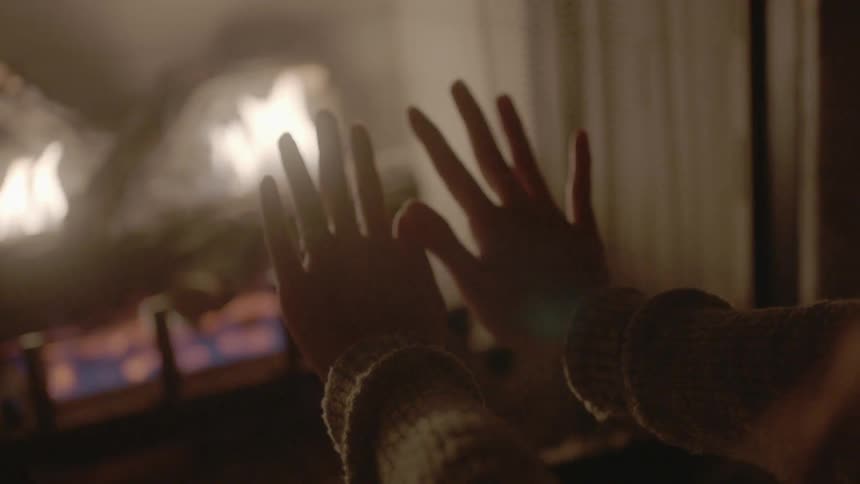 A person warms their hands by a fire