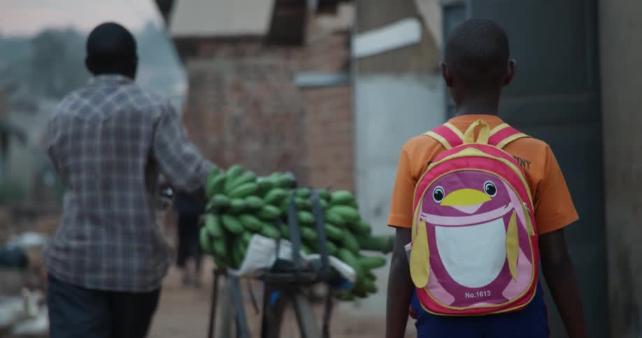 A boy is carrying a bushel of bananas on a bike