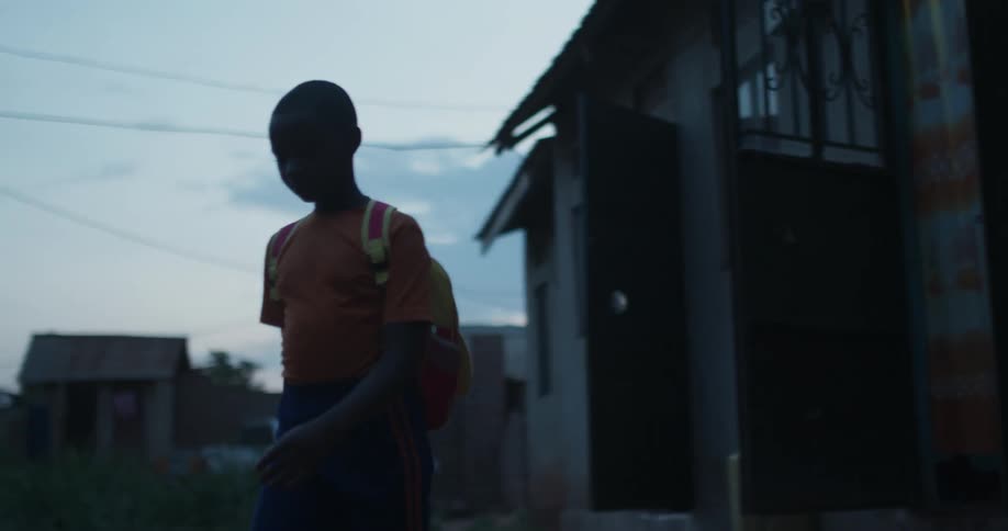 A boy walks out of his home with his backpack
