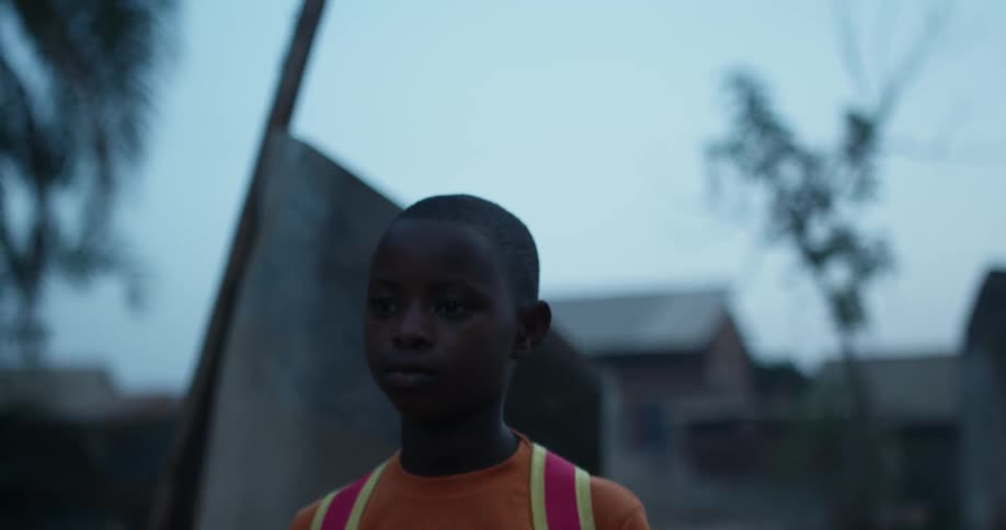 A child with a backpack walks outside