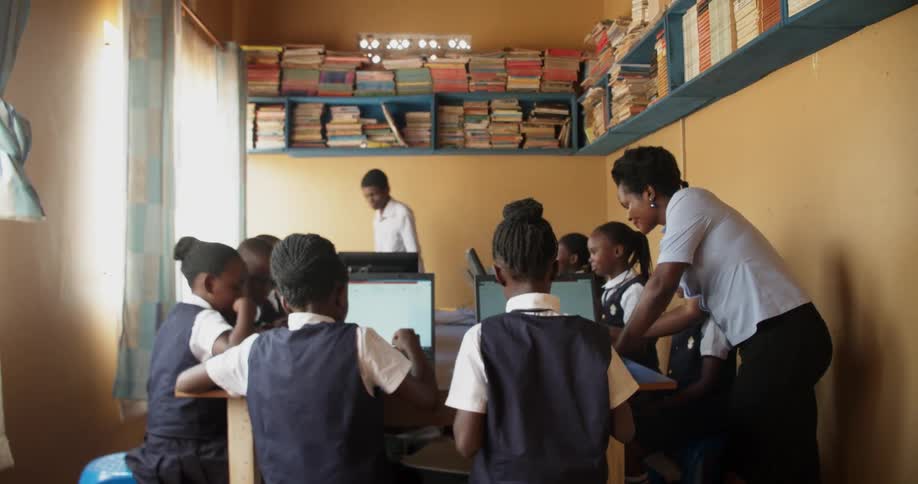 Teachers help students working on laptops