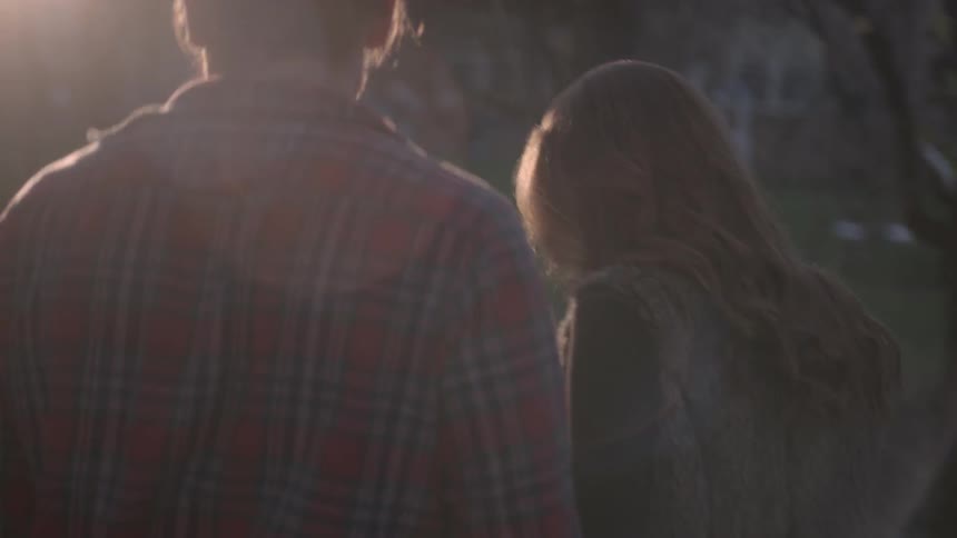 A young couple stroll hand in hand in a wooded area