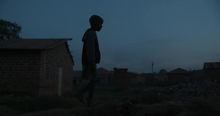 Child walks outside near houses at night