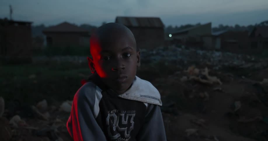 A boy sits near a town at dawn