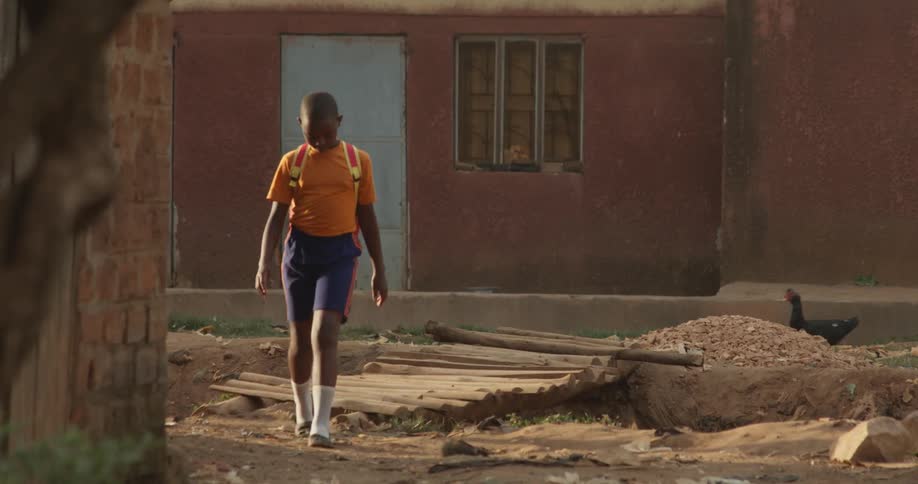 Child walks over a wooden bridge in a village